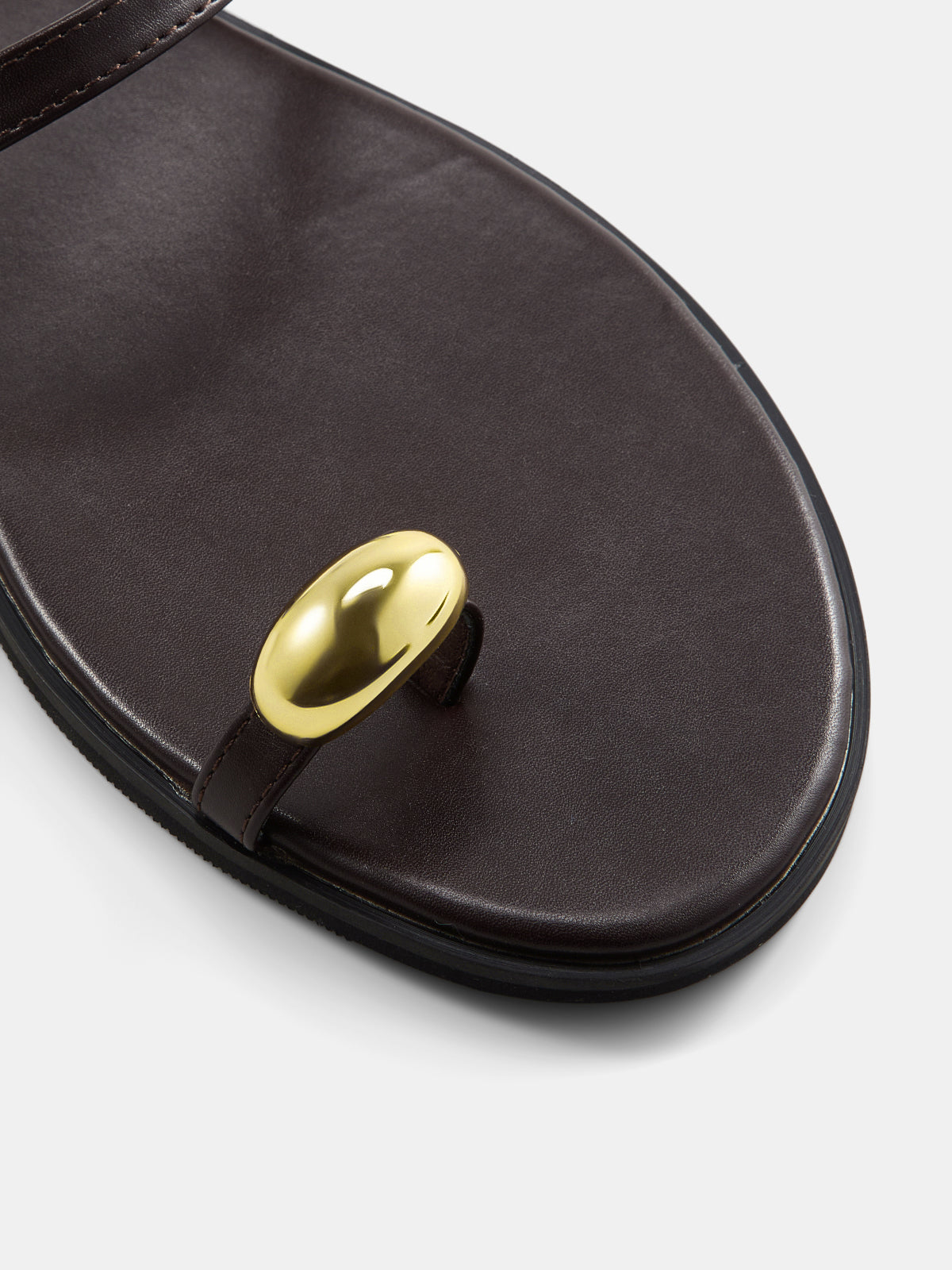 Sandalias planas con tira entre los dedos y detalles metálicos